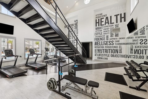 Fitness center with stairs, weights, and motivational wall art at The Duke at Charleston Ladson, SC homes for rent.