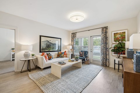 A living room with a white sofa, a coffee table, and a painting on the wall.
