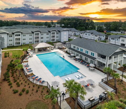 Aerial view of The Duke at Charleston apartment community and resort-style pool at sunset in Ladson, SC.
