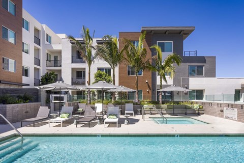 a swimming pool with chairs and umbrellas in front of a building