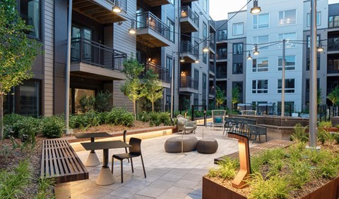 a courtyard with tables and chairs in an apartment complex