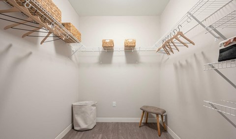 a walk in closet with shelves and a stool