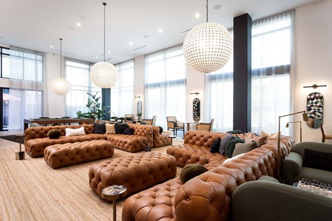 A living room with a large sectional sofa and a long row of tufted ottomans.