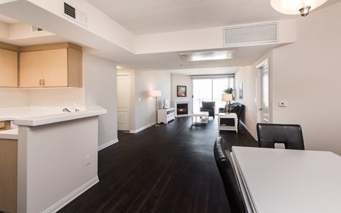 a living room and dining room with white walls and wood floors