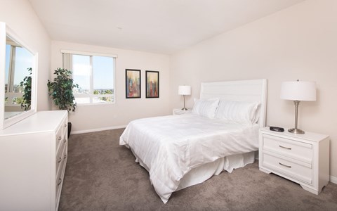 a white bedroom with a white bed and a window