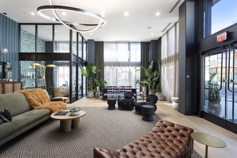 A modern living room with a green couch and a brown leather ottoman.