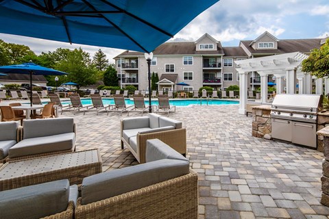 a large pool with chairs and umbrellas and a building in the background