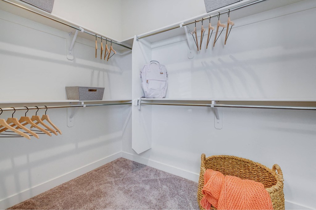 a walk in closet with a basket and hangers