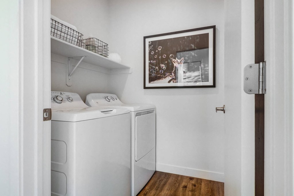 a small laundry room with a washer and dryer and a painting on the