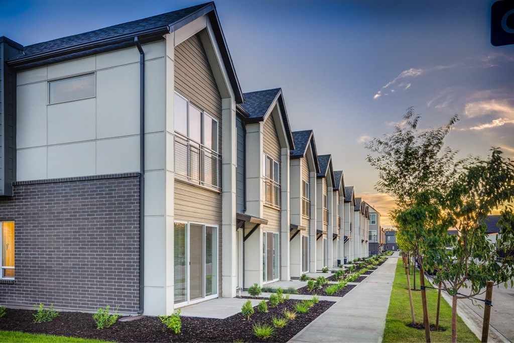 a row of townhouses with a sidewalk in front of them