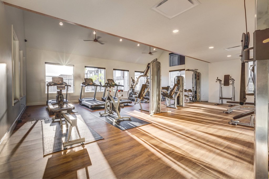 a gym with cardio machines and weights on a wooden floor