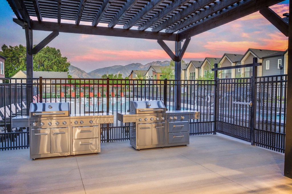 a patio with two stainless steel barbecue grills and a gazebo
