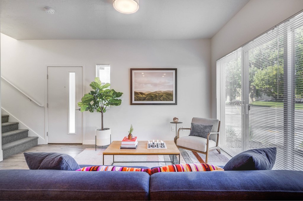 a living room with a couch and a chair and large windows