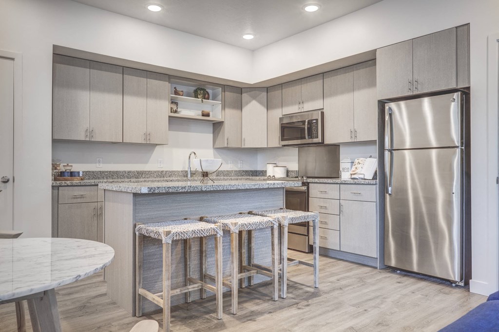 a kitchen with stainless steel appliances and a bar with three stools