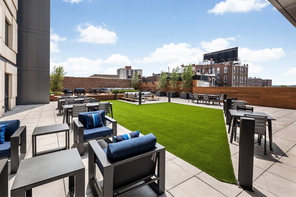 A patio with blue cushions and chairs overlooks a grassy area.