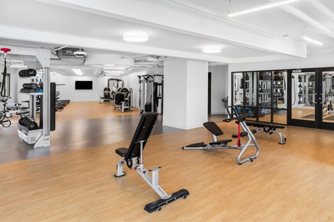 a gym with weights and cardio equipment in a room with wood floors