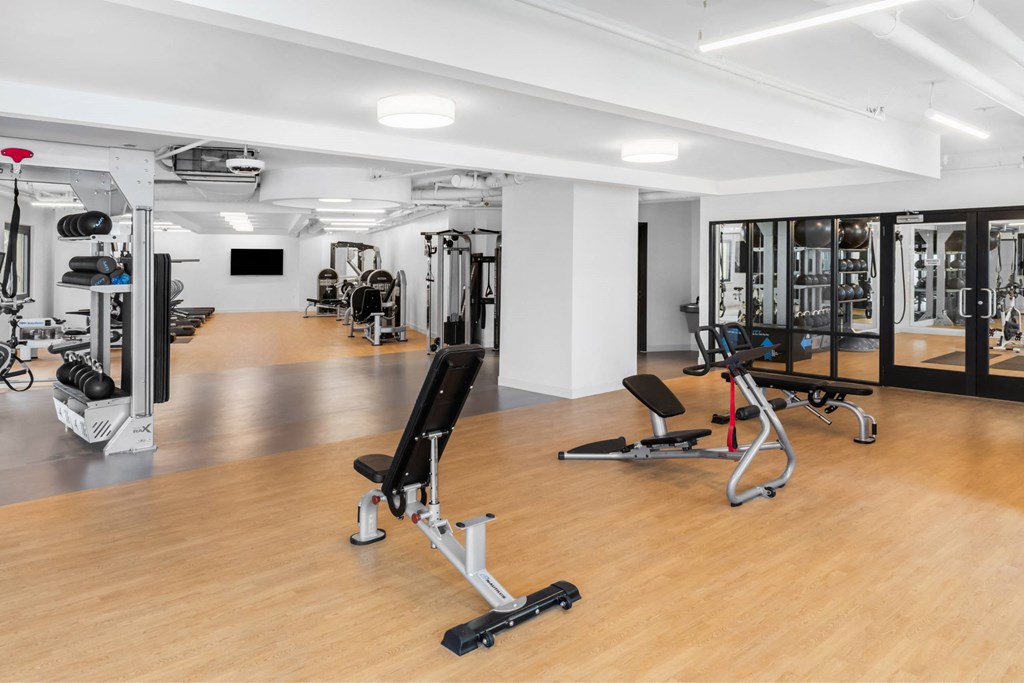 a gym with weights and cardio equipment in a room with wood floors