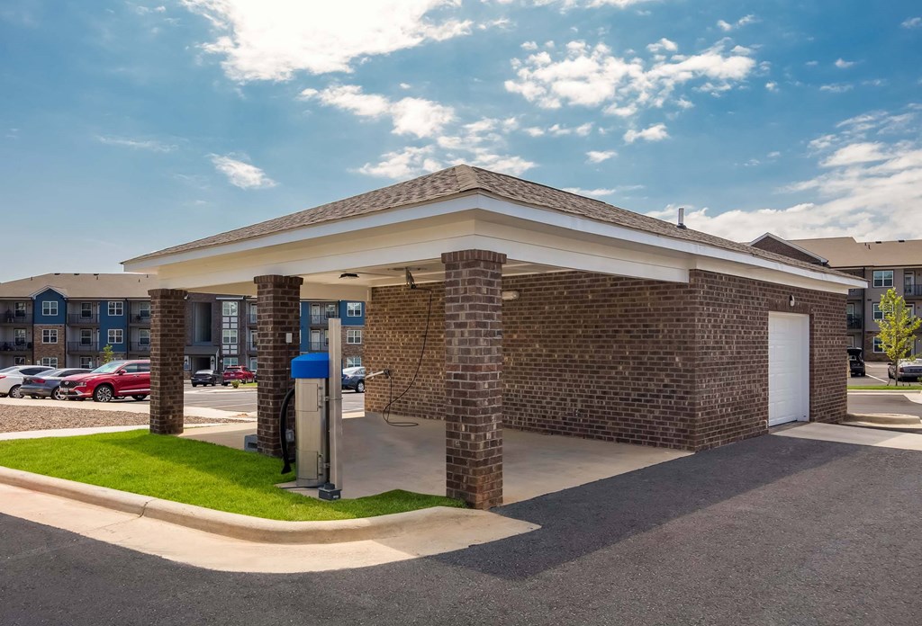 A brick building with a covered parking area in front.