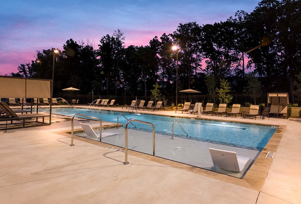 a swimming pool at dusk with chairs around it