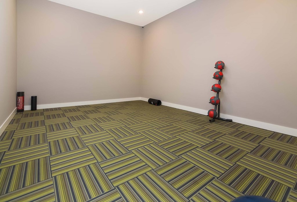 A room with a striped carpet and a red fire extinguisher on the wall.