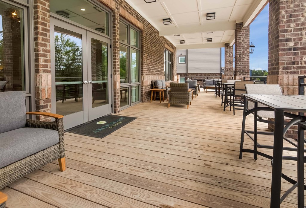 A patio with a grey couch and a black mat.