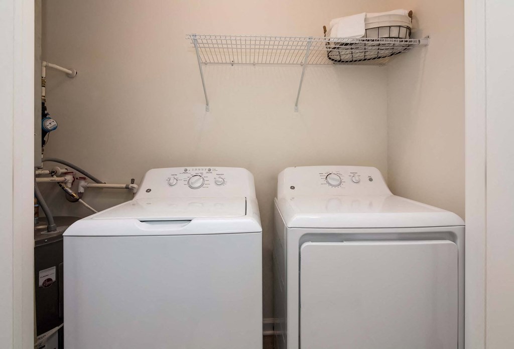 Two white front loading washing machines in a small laundry room.