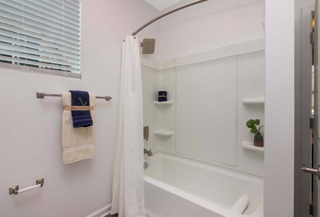 A white bathroom with a white tub and a white shower curtain.