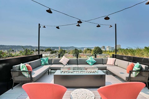 A rooftop patio with a table, chairs, and a view of the city.