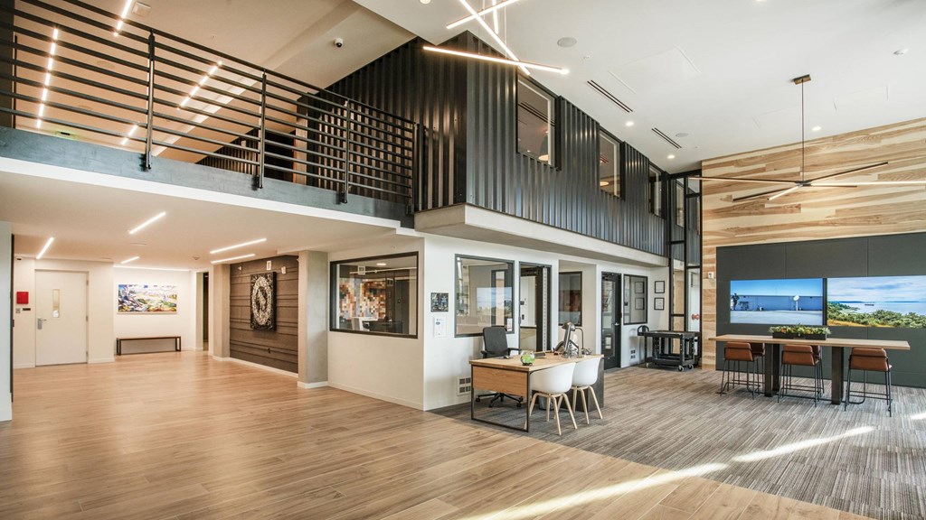 A modern interior space with a wooden floor and a balcony with a railing.at Axle, Seattle, 98119