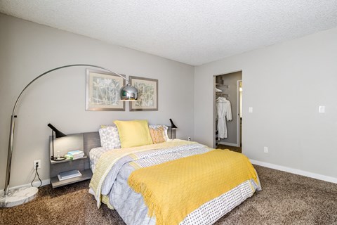 A bedroom with a bed and a yellow blanket.