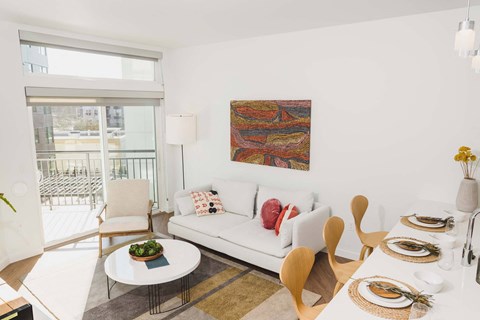 A modern living room with a white couch and a painting on the wall.