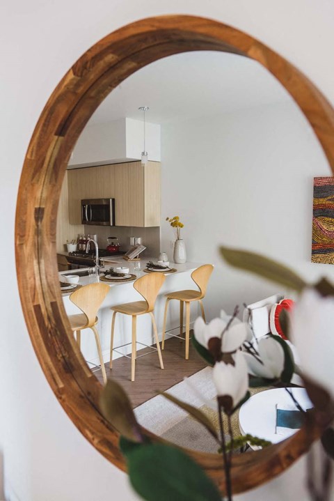 A round mirror reflects a dining room with a table set for two.