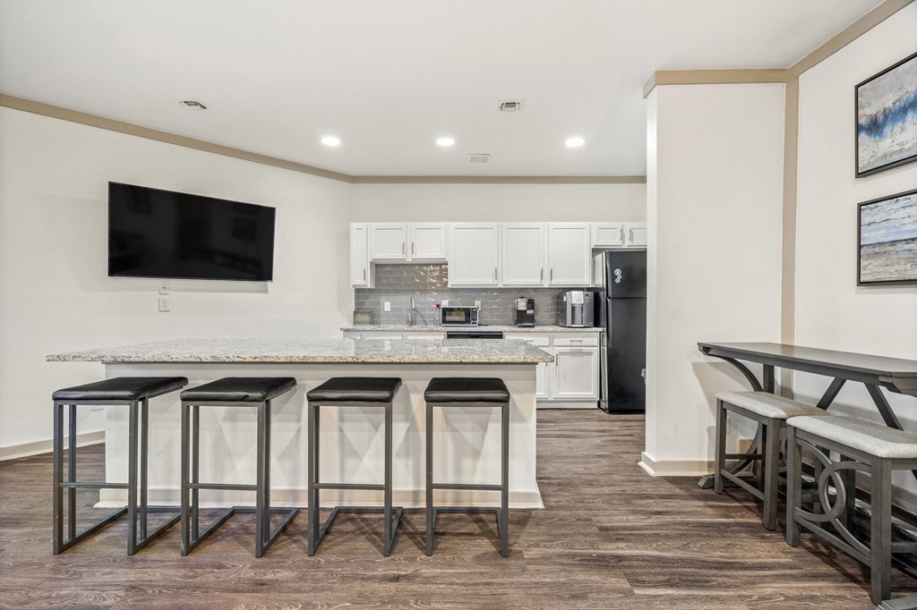 A kitchen with a bar area and a television mounted on the wall.