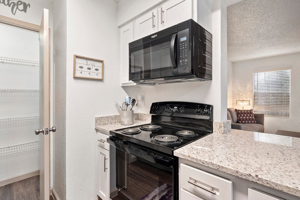 A black microwave is mounted above a black stove in a kitchen.