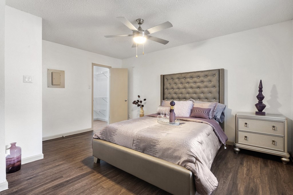 A bedroom with a bed, dresser, and ceiling fan.