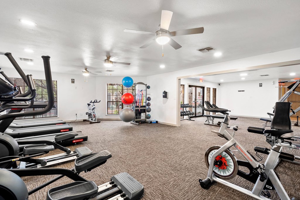 A spacious gym with a variety of equipment including treadmills, stationary bikes, and weight machines.