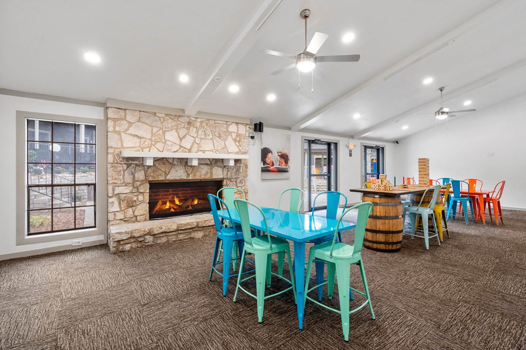 A room with a stone fireplace and a table surrounded by chairs.
