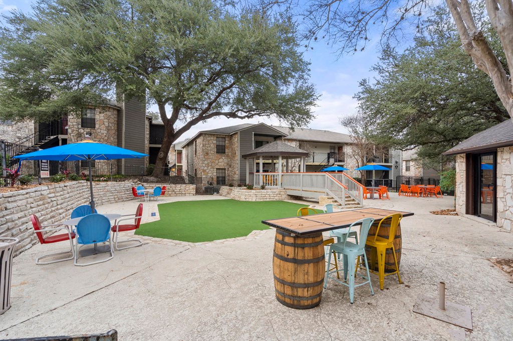 A backyard with a green lawn, a barrel table, and chairs.