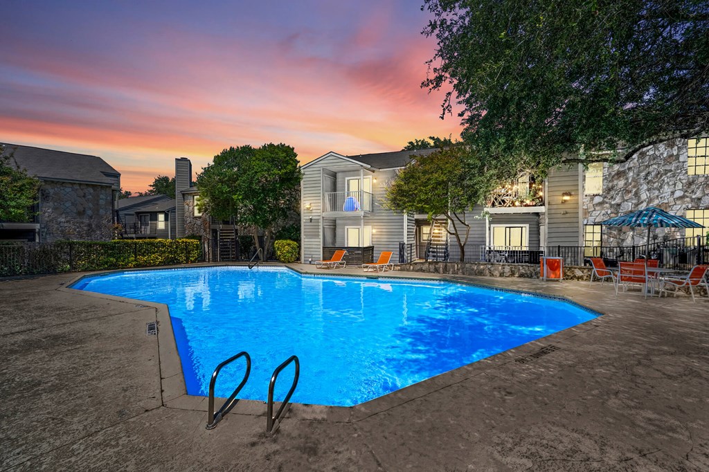 A swimming pool surrounded by a fence and a building in the background.