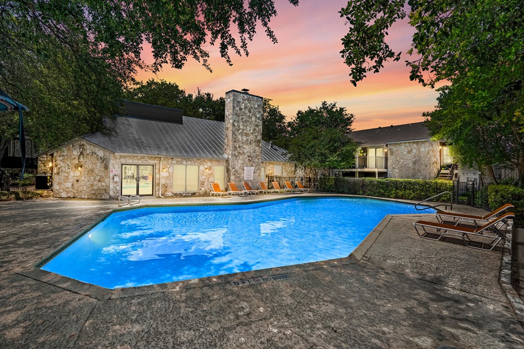 A swimming pool surrounded by trees and a house in the background.