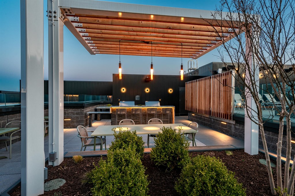 A patio area with tables and chairs under a wooden pergola.