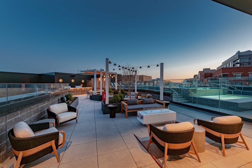 A rooftop patio with wicker chairs and tables.