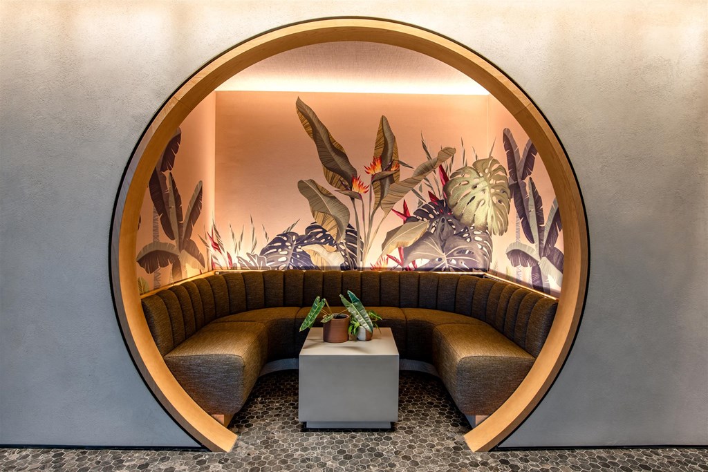 A round, wooden frame with a mural of plants and animals on the wall behind a bench.