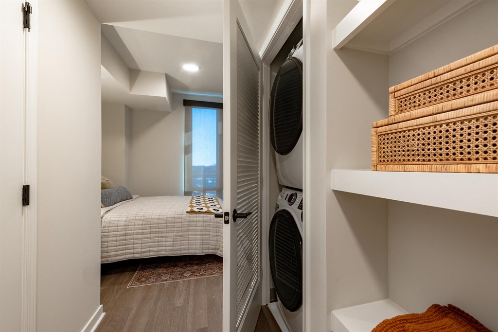 A bedroom with a bed, a window, and a shelf with a basket on it.