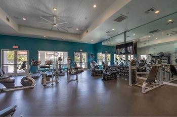 A spacious gym with a variety of equipment and a ceiling fan.