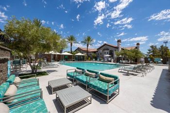 A pool area with sun loungers and a building in the background.