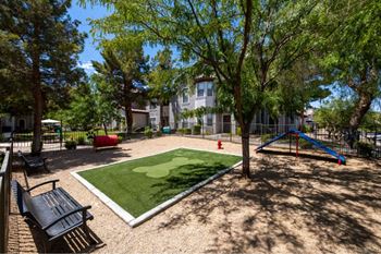 A playground with a green artificial turf and a slide.