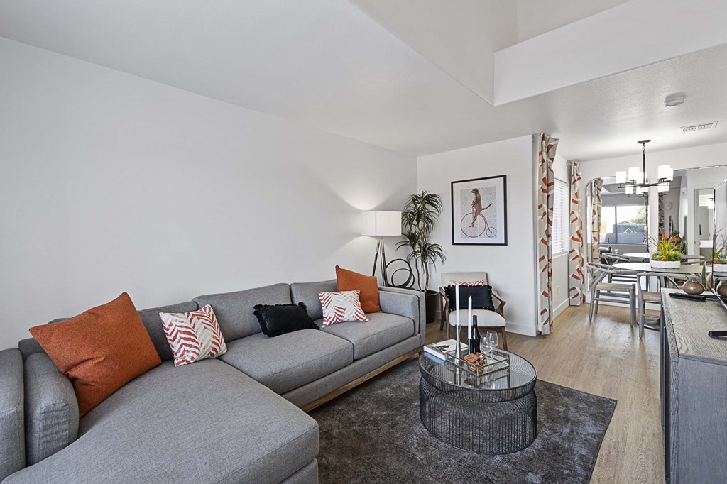A grey sofa with orange and white pillows sits in a living room.