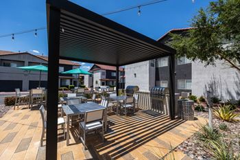 A patio with a table and chairs under a black awning.