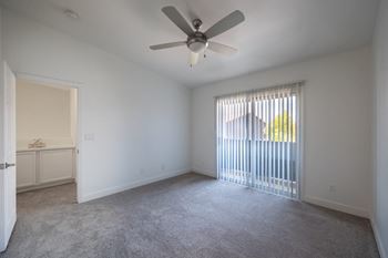A room with a ceiling fan and carpeted floor.